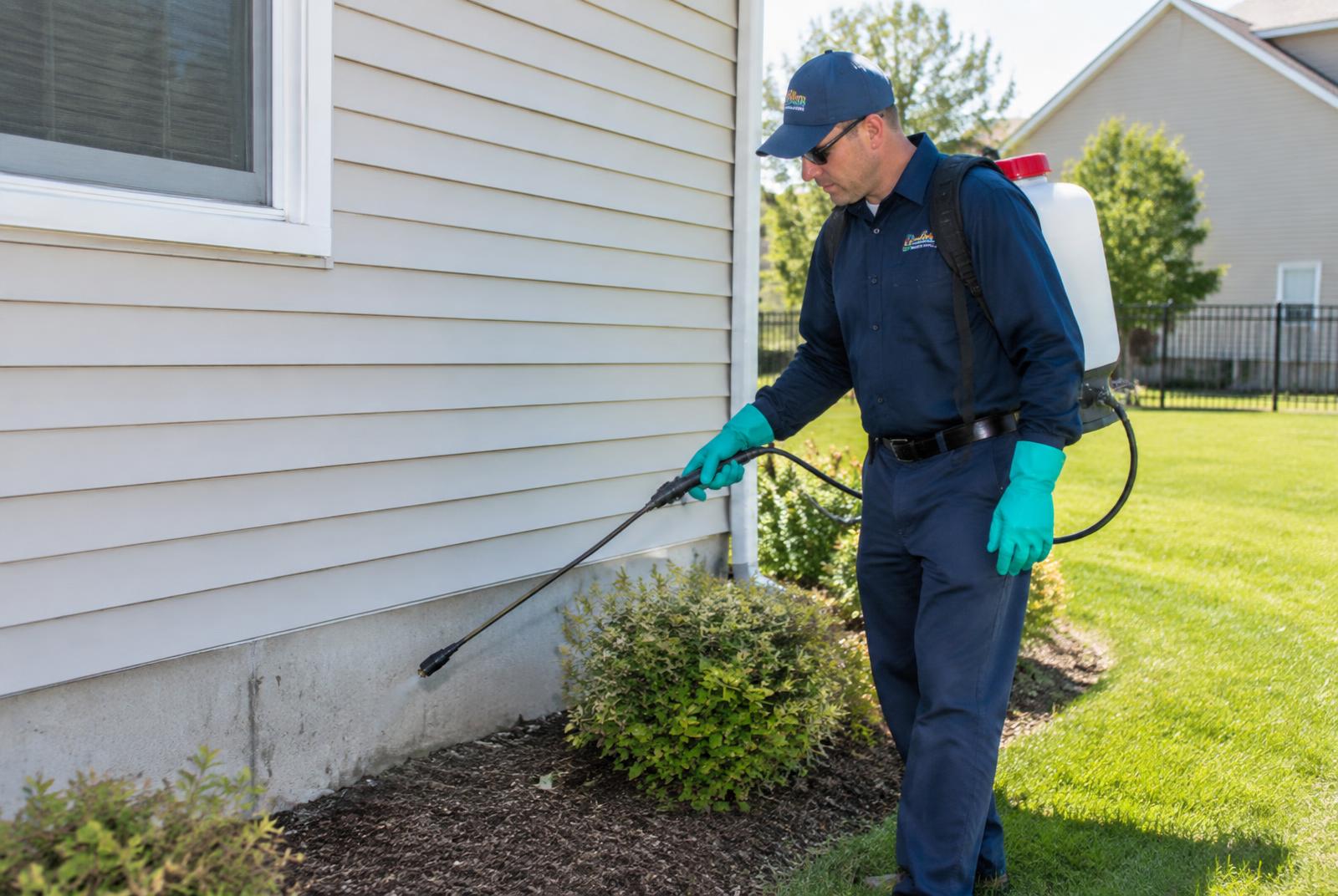 Exterior perimeter pest treatment Pest control technician spraying a perimeter treatment along the foundation of a home in Anderson, Indiana